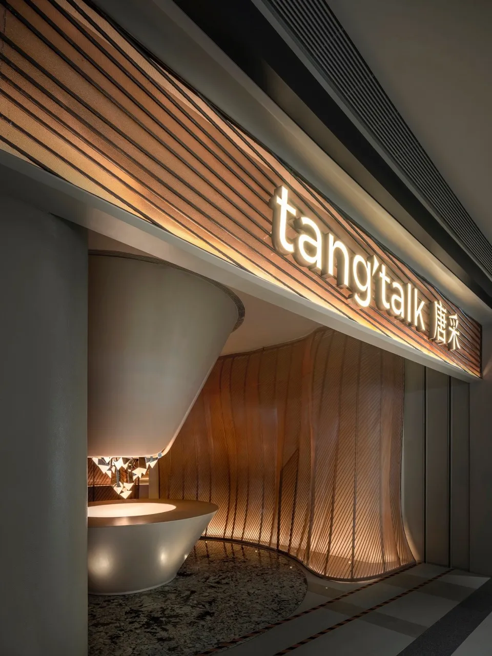 Modern showroom with a large white marble sink, illuminated by several lights, creating a bright and inviting atmosphere