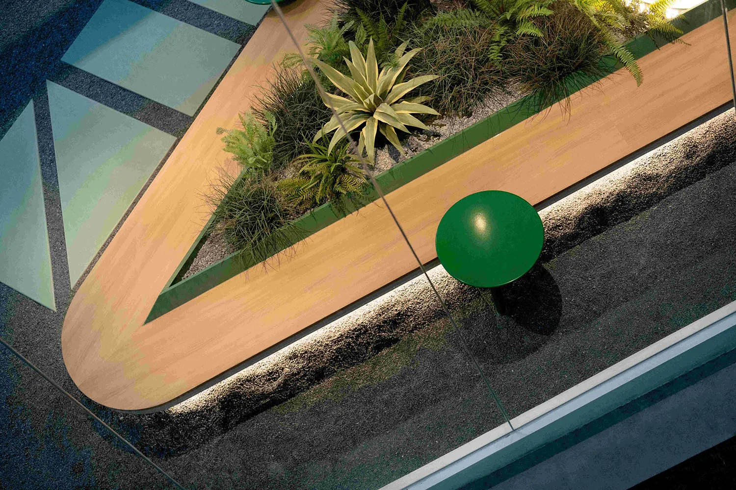 A serene indoor space with a wooden table surrounded by lush greenery and natural elements, creating a peaceful atmosphere