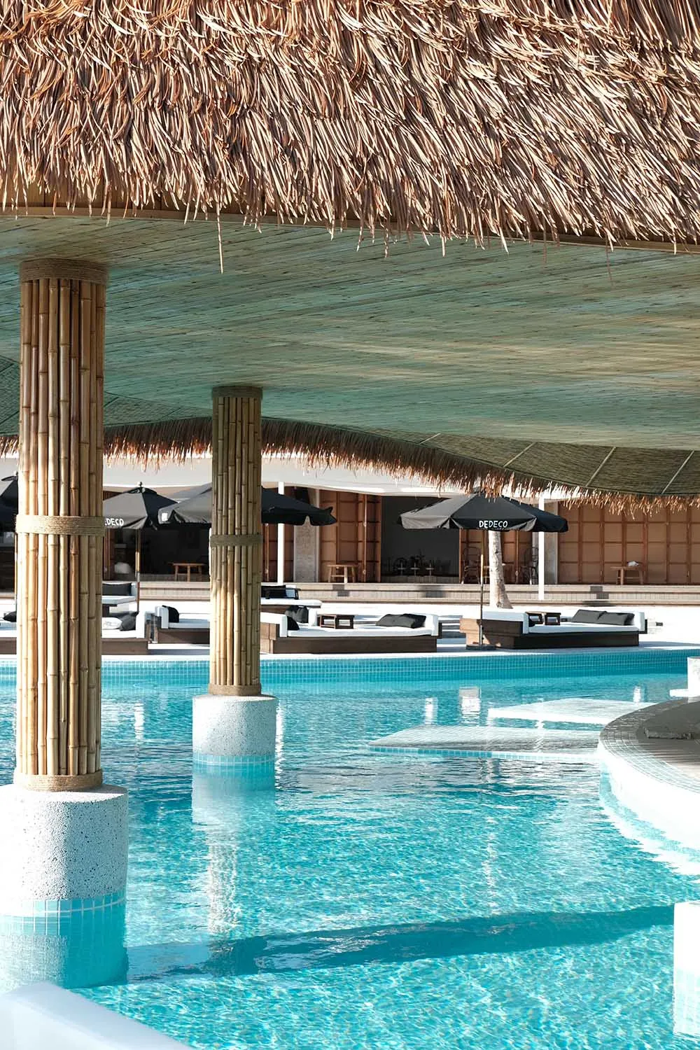A pool area with a large pool surrounded by chairs and umbrellas, providing a comfortable outdoor space for relaxation
