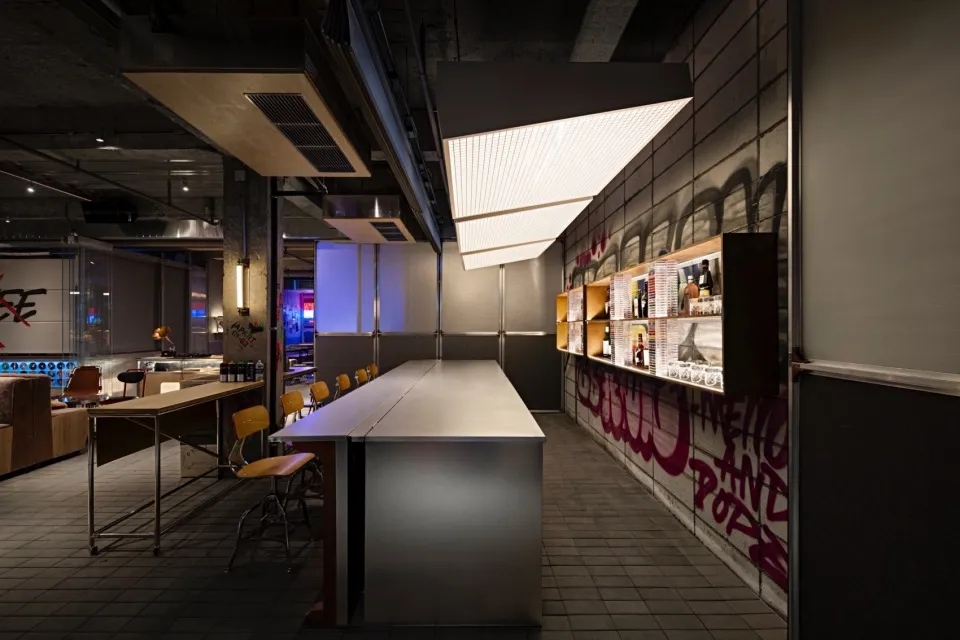 Modern kitchen with a large countertop, chairs, and bottles, featuring a functional and efficient design