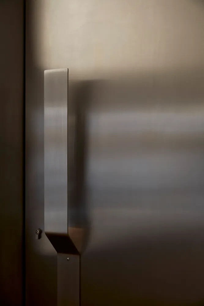 A doorway with a stainless steel door and metal frame, leading into a hallway with a sense of depth and dimension