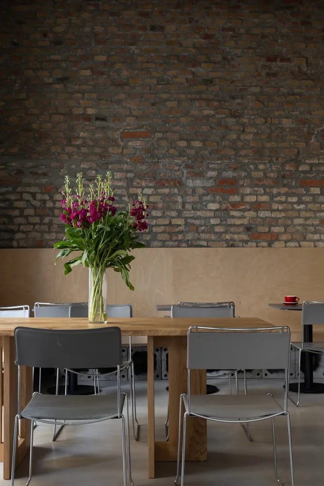Inviting dining space with exposed brick walls, a wooden table, and a vase of flowers, surrounded by chairs and a potted plant