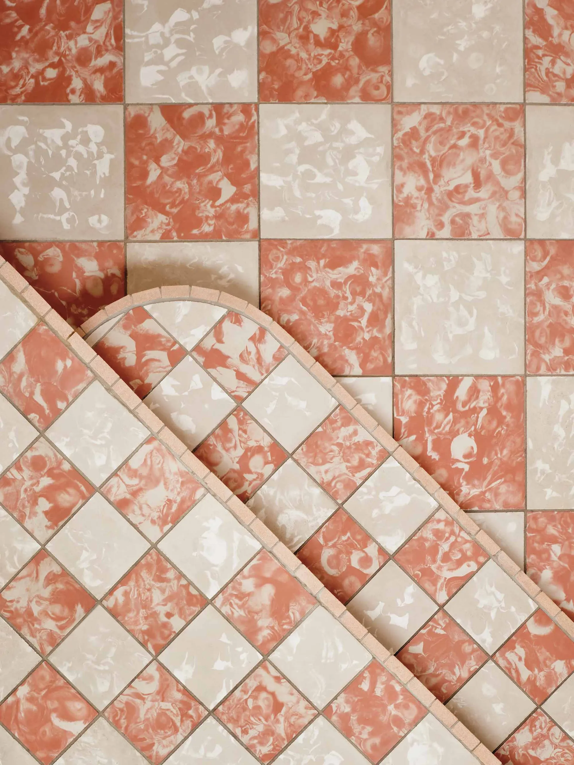 Pink tiled wall with a white border and a checkered pattern of red and white squares in a bathroom or kitchen area