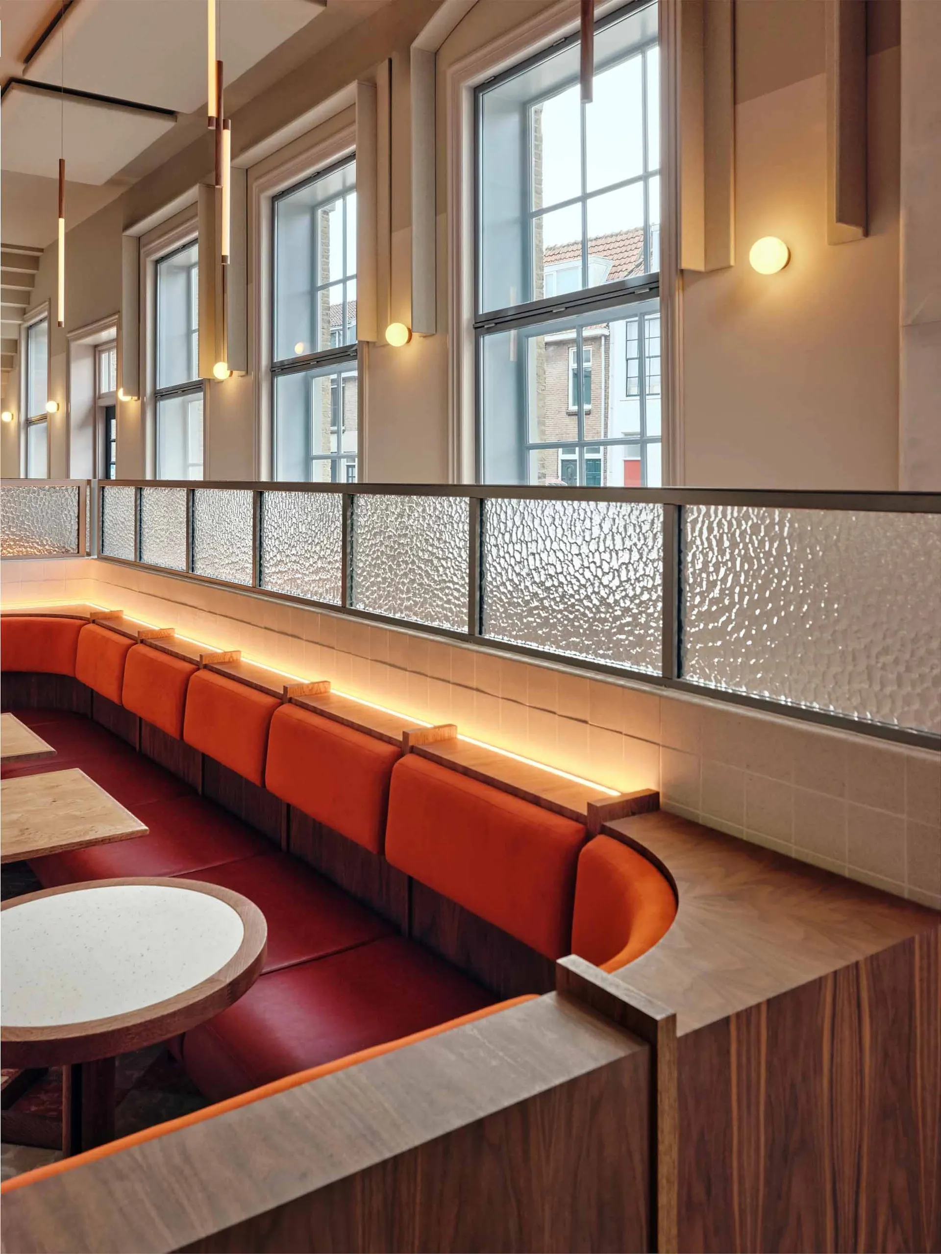 rows of wooden benches and dining tables in a restaurant or cafeteria with natural light from windows