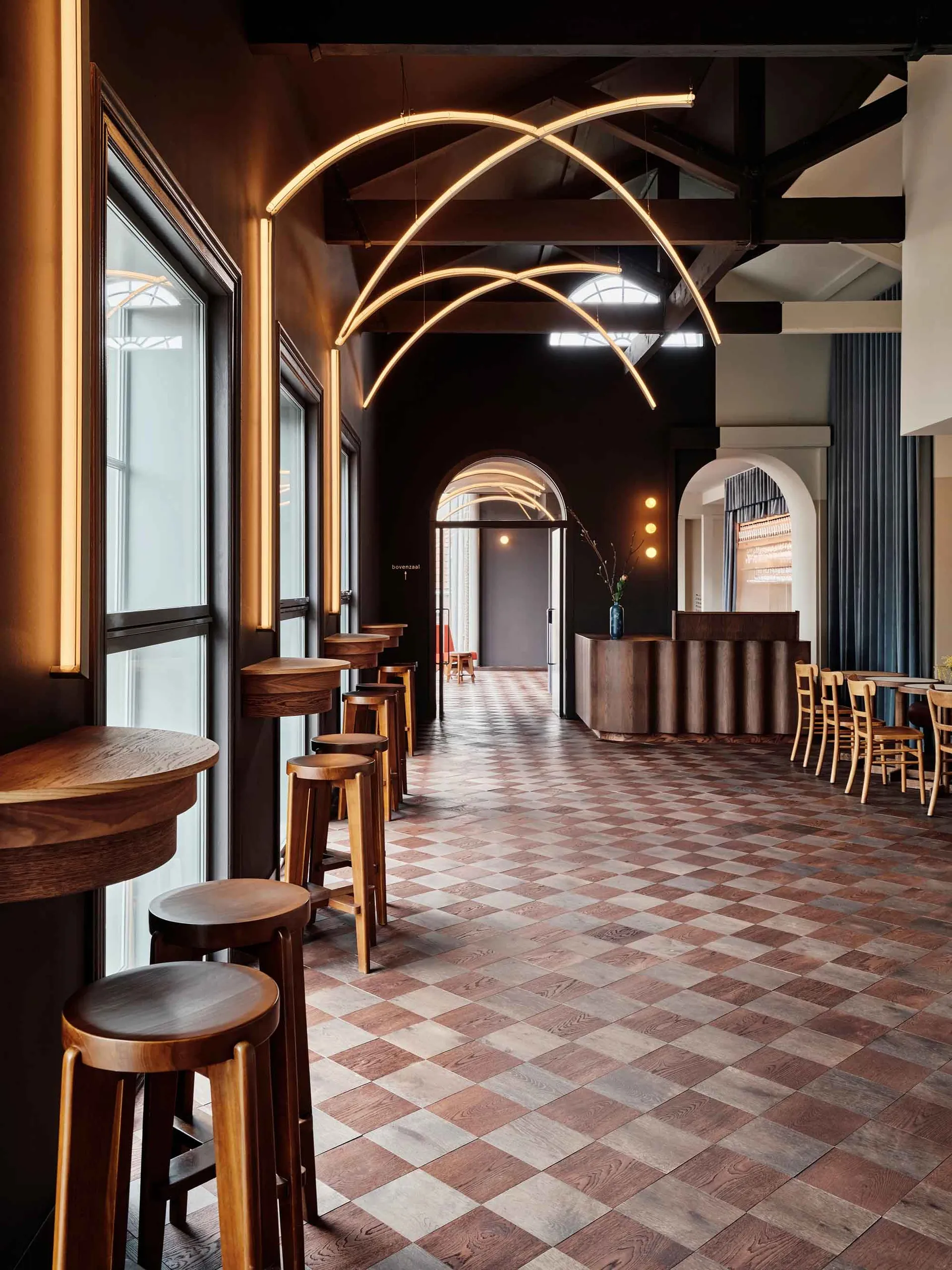 Cozy restaurant with a wooden floor, black walls, and chairs arranged around dining tables in various positions throughout the space