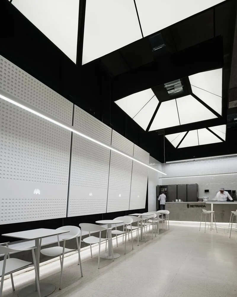 Empty restaurant interior with white walls, dining tables, and comfortable seating arrangement, featuring modern simplicity and well-planned lighting