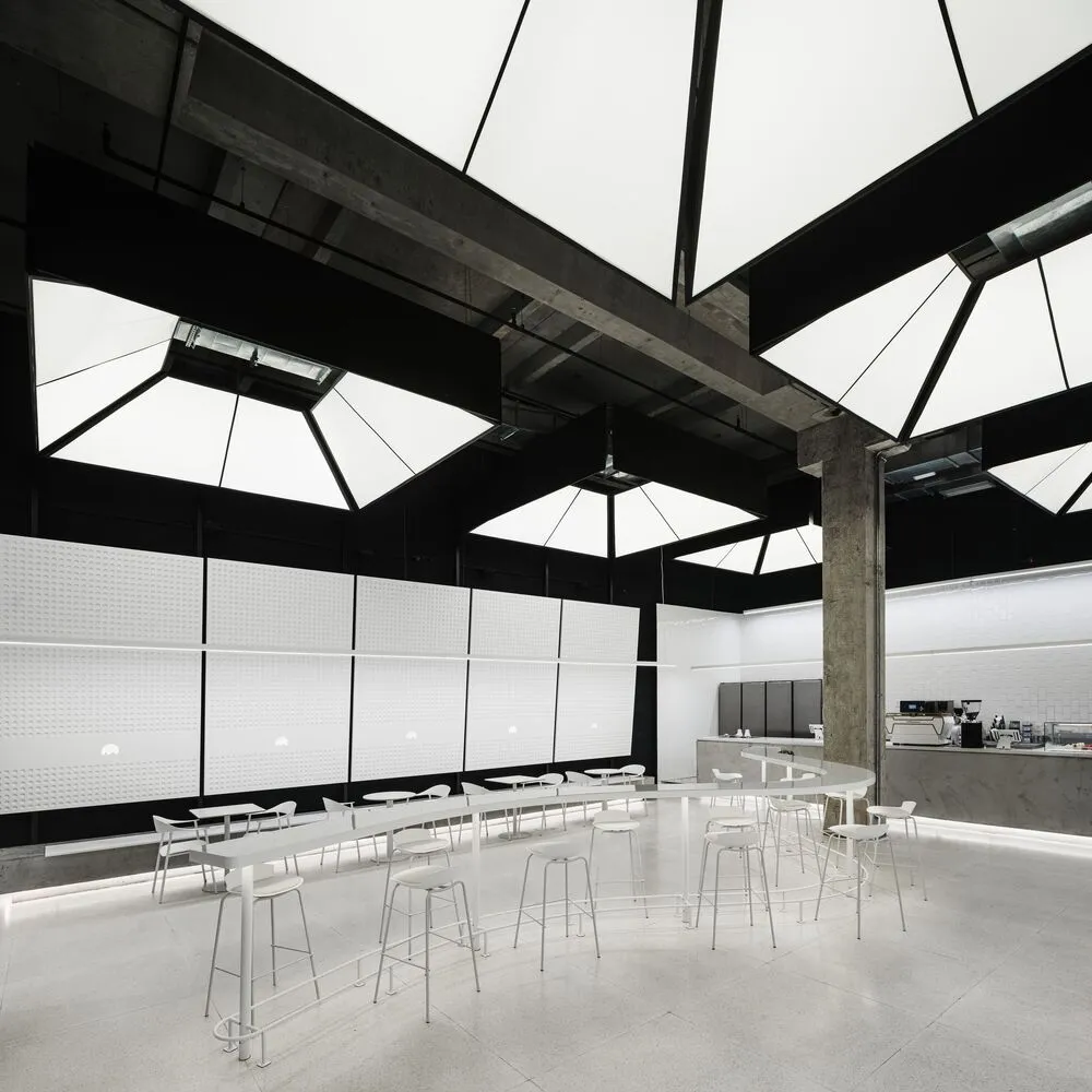 Modern restaurant interior with white walls, tiled and carpeted flooring, and multiple dining tables and chairs
