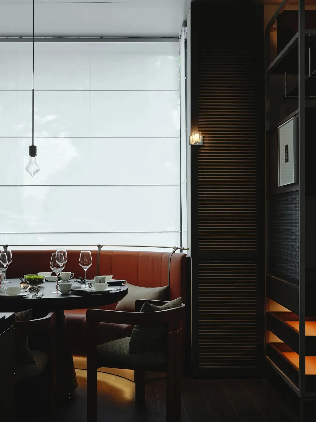 Sophisticated dining area with a large window, multiple chairs, and wine glasses on a dining table