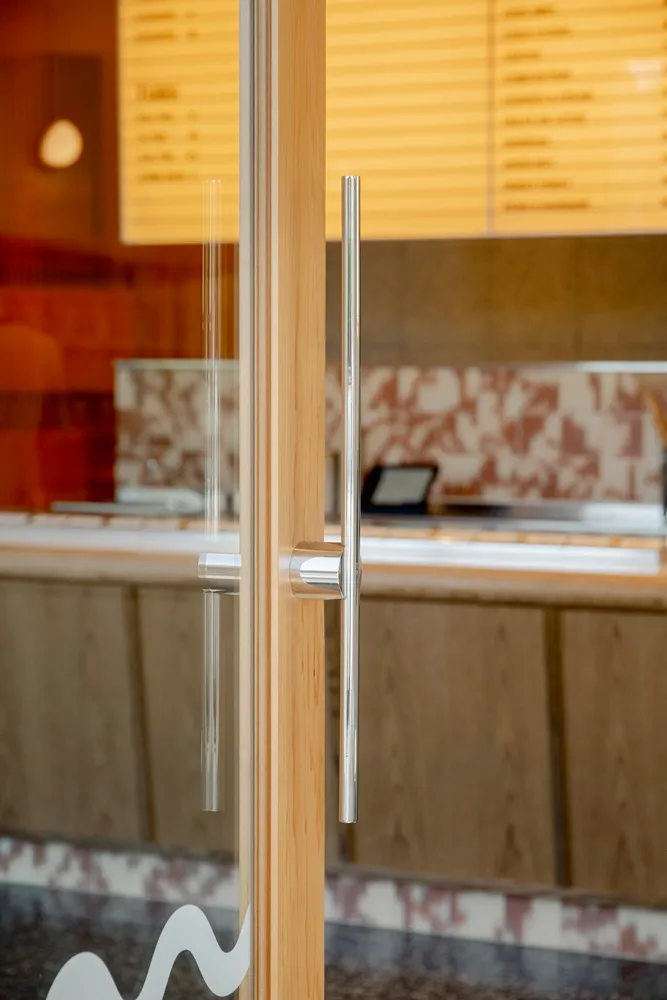 Casual restaurant interior with wooden doors and counter, people in the background enjoying meals