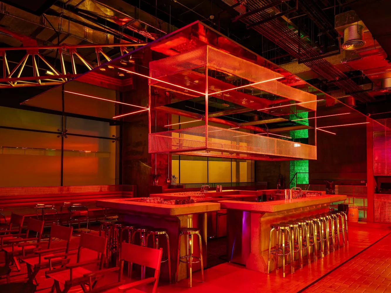 Modern industrial kitchen with red walls, a wooden countertop, and multiple chairs around the dining area
