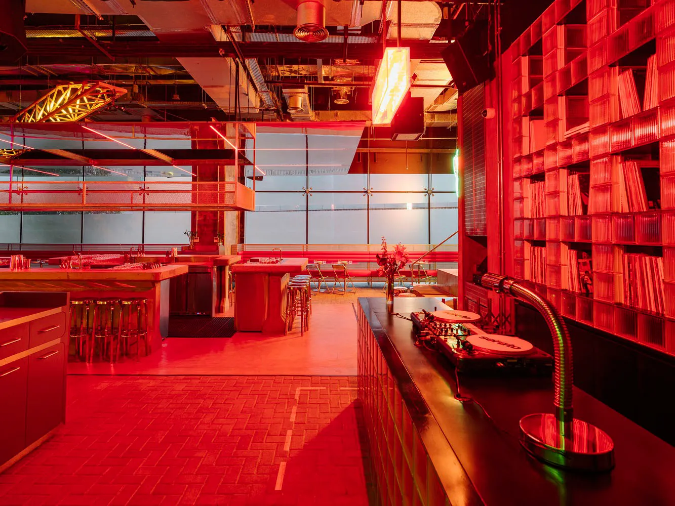 A modern restaurant interior with red walls, a dining table, and comfortable seating for patrons, featuring a warm and inviting atmosphere