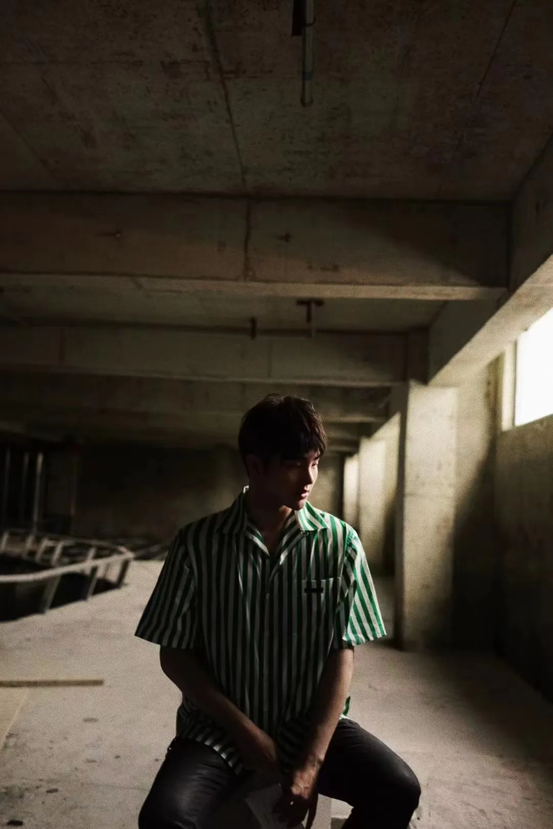 A man stands in a room with a concrete wall and cement floor, giving it an industrial feel