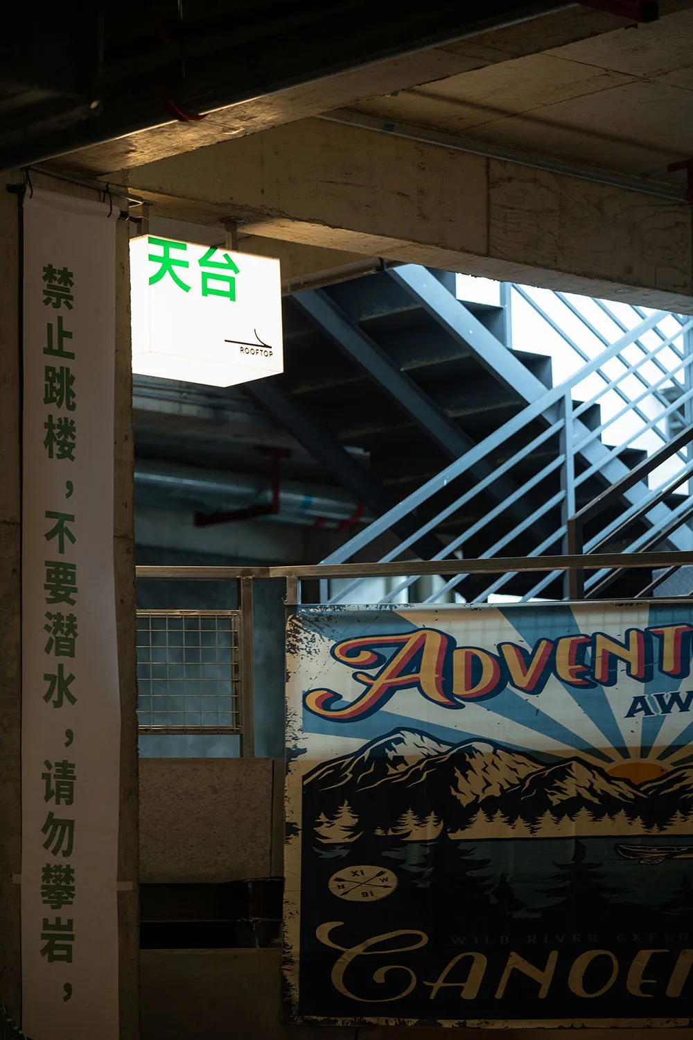 A vintage metal sign in front of a concrete staircase, possibly leading to an underground area, with a sense of exploration and discovery