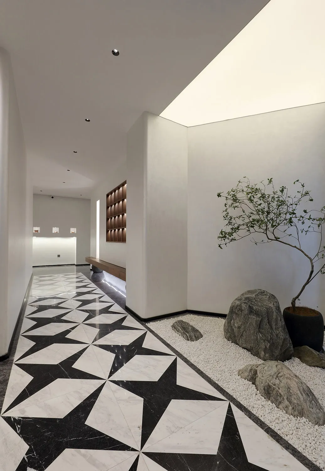 A large white room with a black and white checkered floor, benches, and potted plants, creating an elegant and inviting atmosphere
