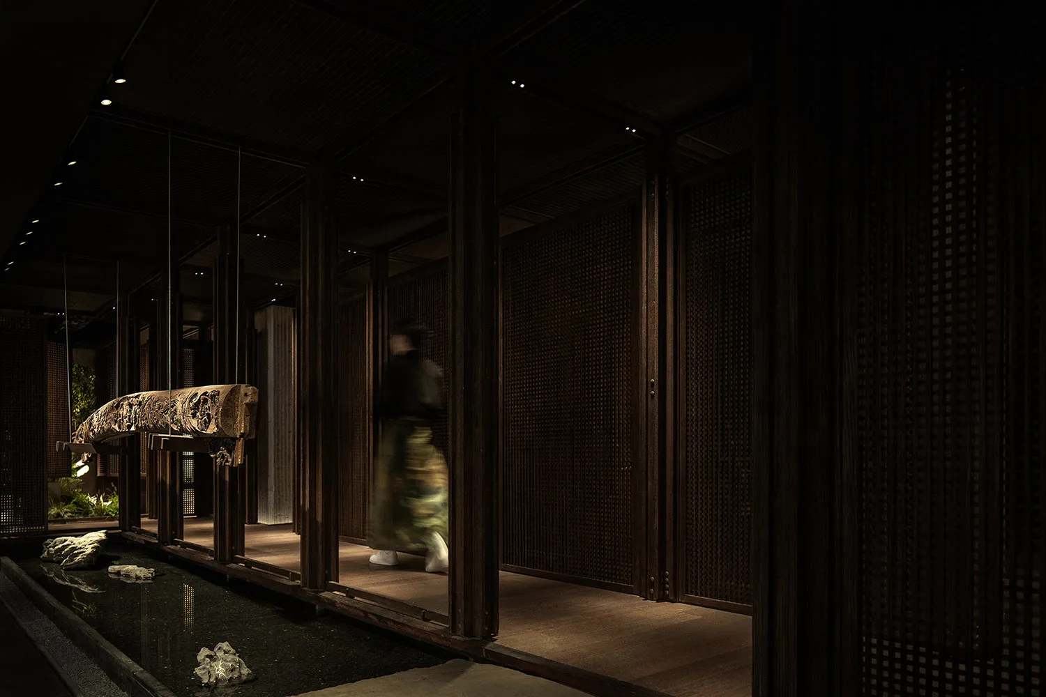 A woman walks down a wooden hallway with two doors, surrounded by classic architectural details