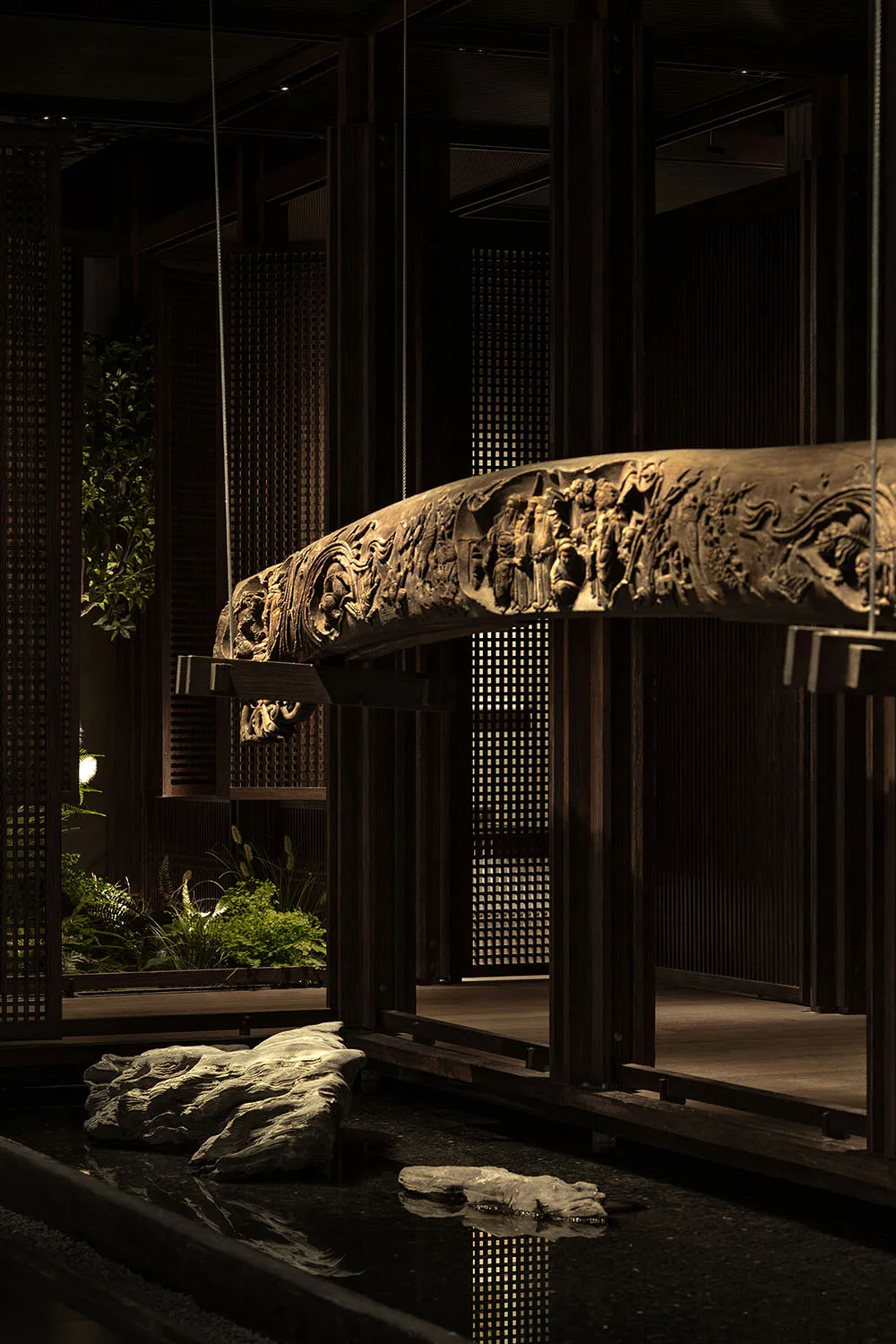 Intricate wooden structure with a large carved beam spanning the width of the image, accompanied by smaller wooden elements and a chair