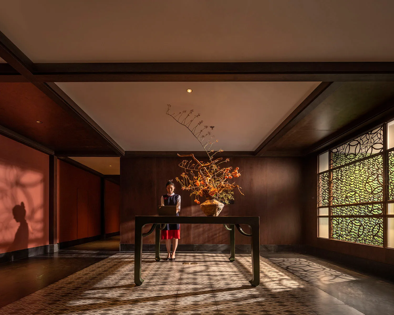 A cozy lobby with a wooden floor, a dining table, chairs, and a vase, creating a comfortable and inviting atmosphere