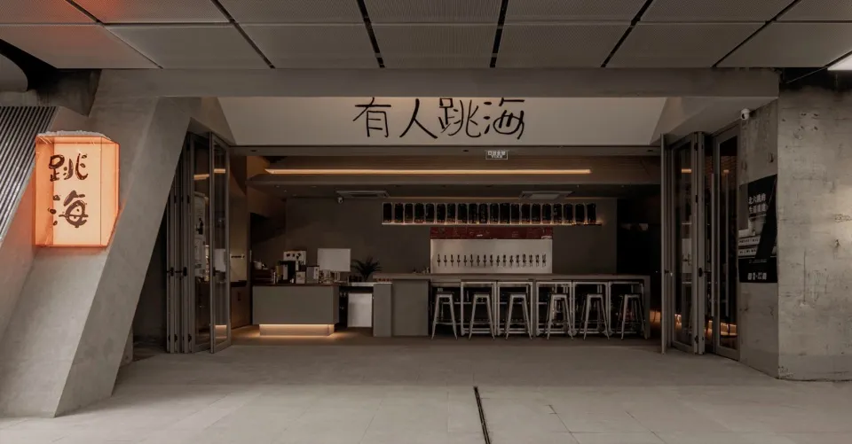 Modern bar area with grey counters, stools, and tables, surrounded by bottles and perfect for socializing