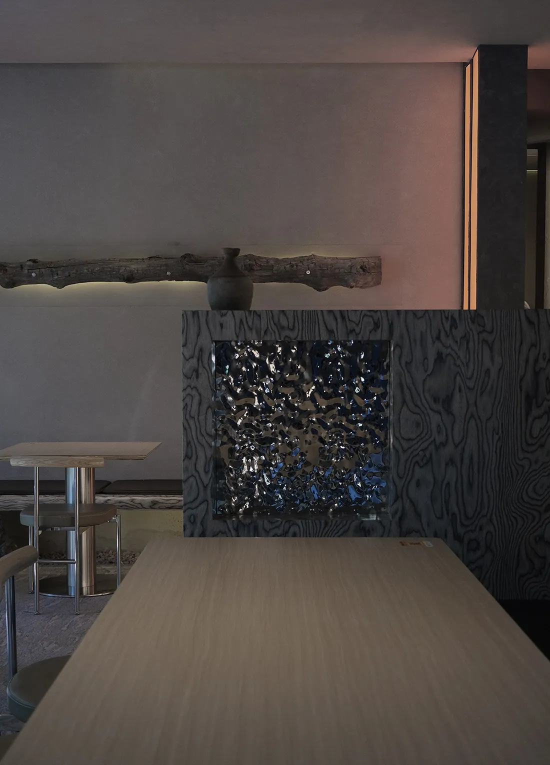 Warm and inviting interior design featuring a wooden table with a glass surface and a large mirror above it, accompanied by two chairs