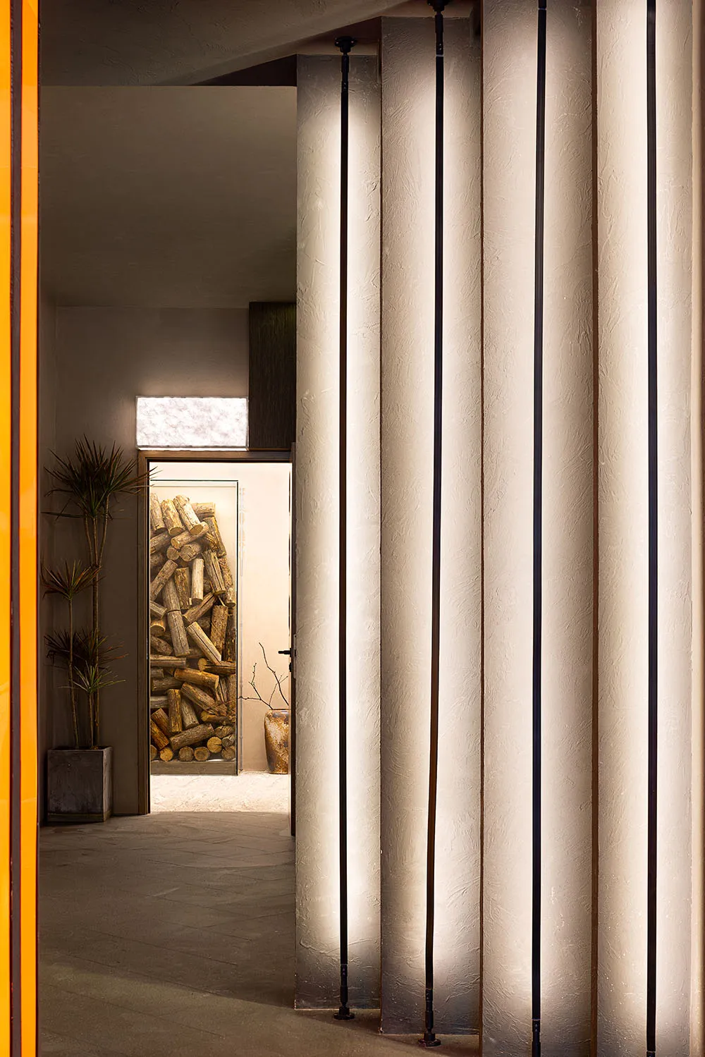 Traditional hallway with wooden surfaces, two potted plants, and a doorway leading to another room