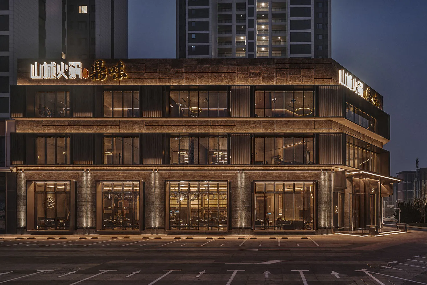 A stone exterior building with many windows, illuminated at night, with outdoor seating and a warm ambiance