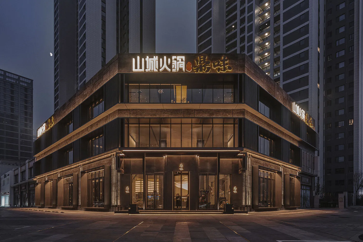 Modern Asian building exterior at night with a large sign on its facade, set against a cityscape
