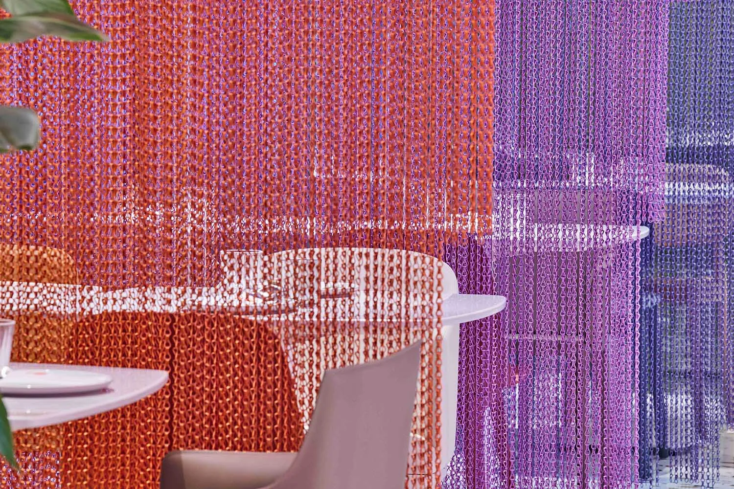 A modern restaurant dining area with a purple and orange color scheme, featuring two chairs and a dining table surrounded by chairs, creating an inviting and comfortable atmosphere