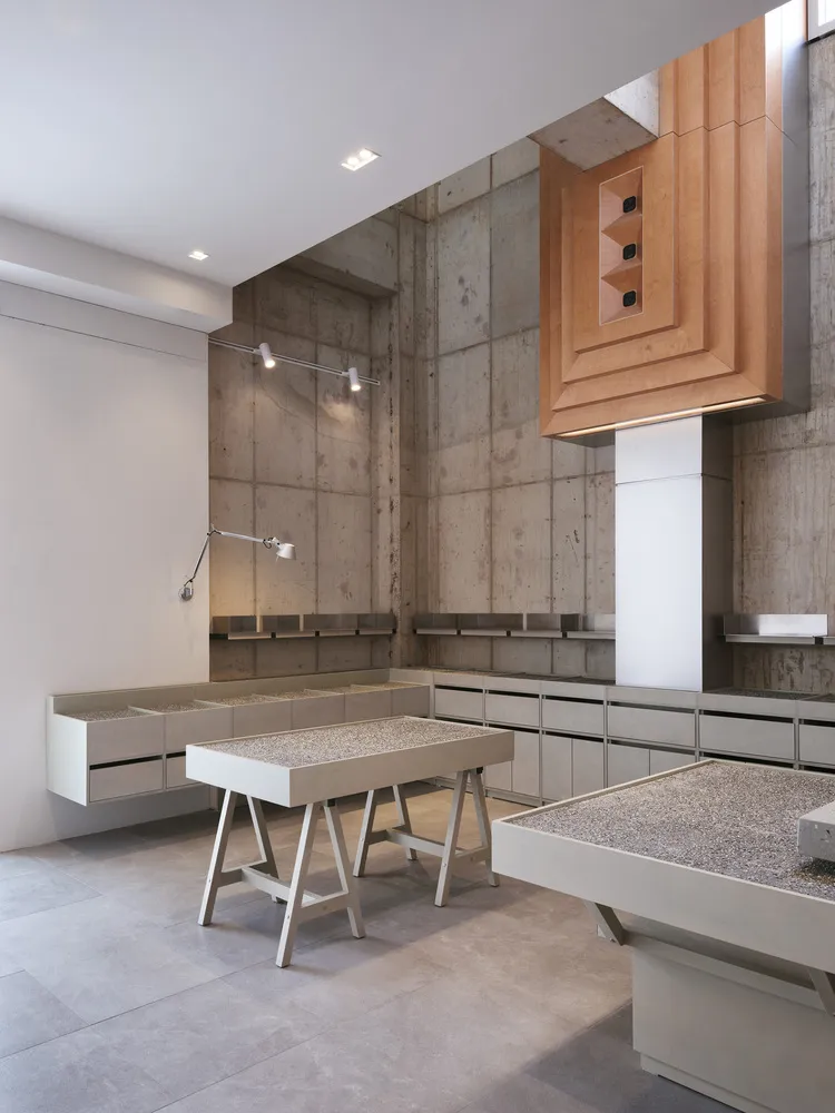 Modern showroom with concrete walls, display tables, chairs, and well-lit atmosphere