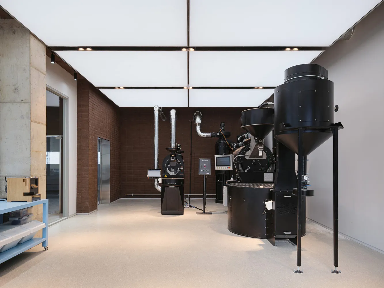 Industrial workspace with two large black silos, machinery, and a TV mounted on one of the silos