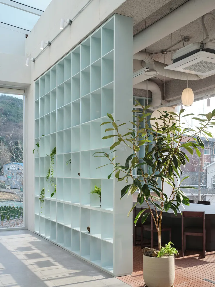 現代客廳或工作空間，設有玻璃牆、書櫃、椅子與餐桌，採光充足