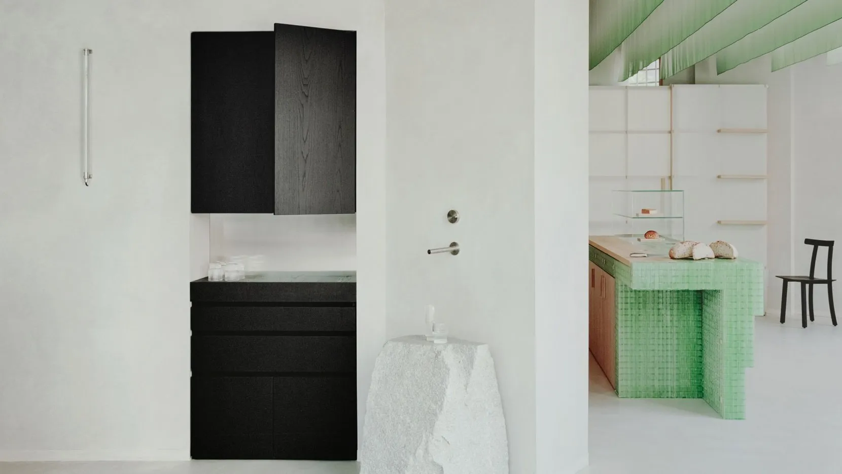A white kitchen with a black cabinet and open drawer, featuring two bottles on the countertop in a clean and organized space