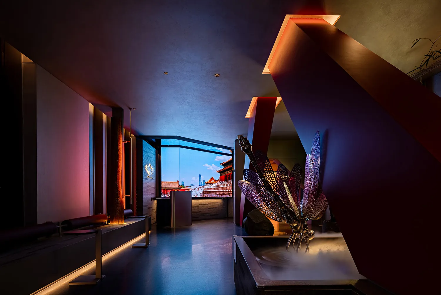 A modern hotel lobby with a mix of red and white elements, featuring potted plants and a vase, set in a spacious area with natural light from a large window