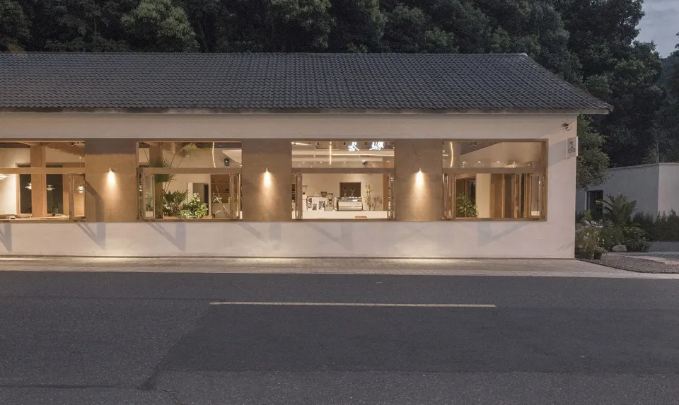 一座磚牆立面的鄉村風建築，周圍環繞盆栽植物與裝飾花瓶，傳達溫暖而親切的氛圍