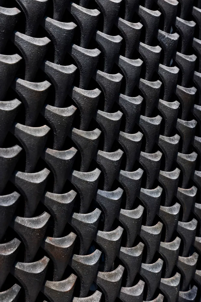 A modern indoor space with a black metal design resembling a brick wall or patterned floor, featuring a combination of materials and patterns, with black metal dominating the scene, and possible hints of gray or silver, in a well-lit environment