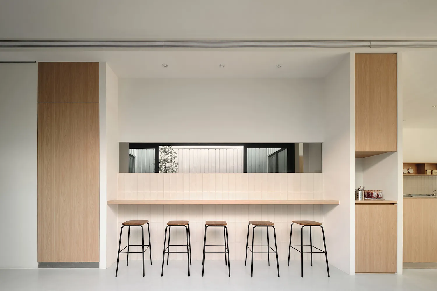 Empty kitchen space with a wooden countertop and four stools, featuring a clean and minimalistic atmosphere