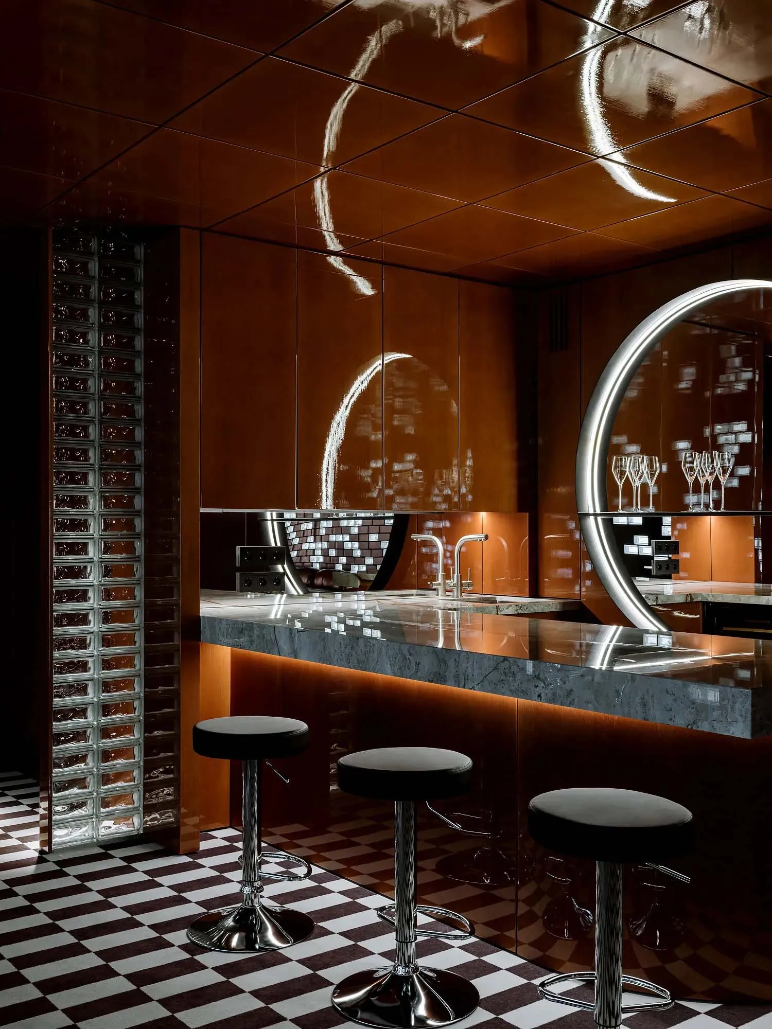 Modern kitchen with a large island, stools, sink, and wine glasses, giving off a sophisticated vibe