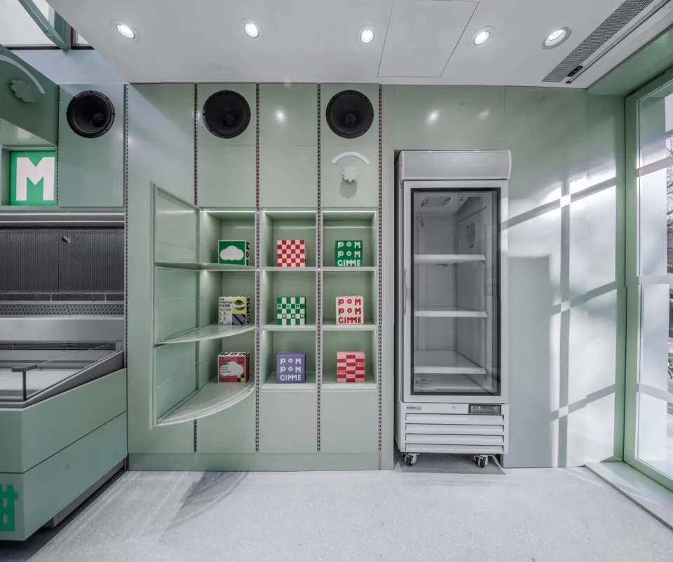 A modern kitchen with green walls, white cabinets, and a refrigerator freezer, featuring multiple shelves with boxes and a clean design