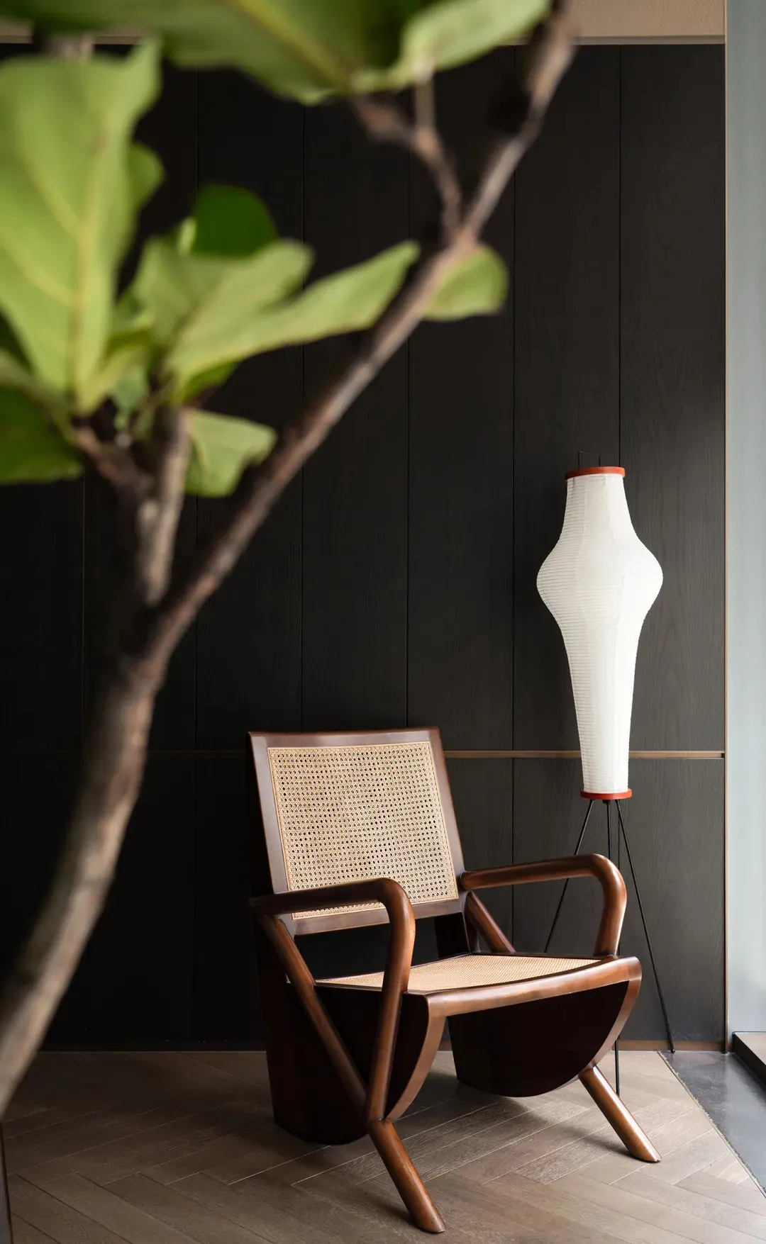 A cozy living area with a wooden chair, two potted plants, and a vase, creating a warm and inviting atmosphere