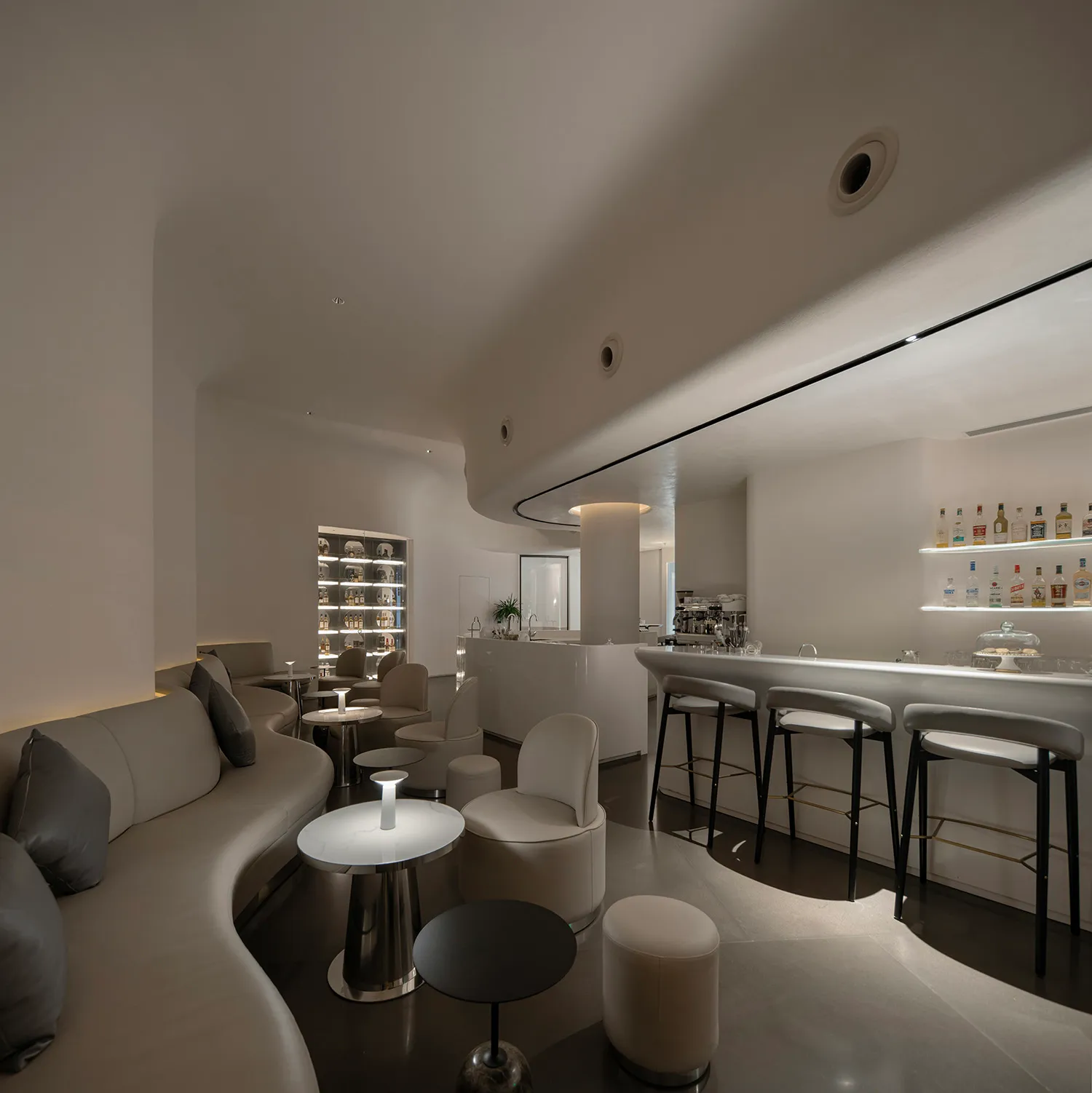 Modern bar area with counter seating, stools, and liquor bottles, set in a stylish and functional space