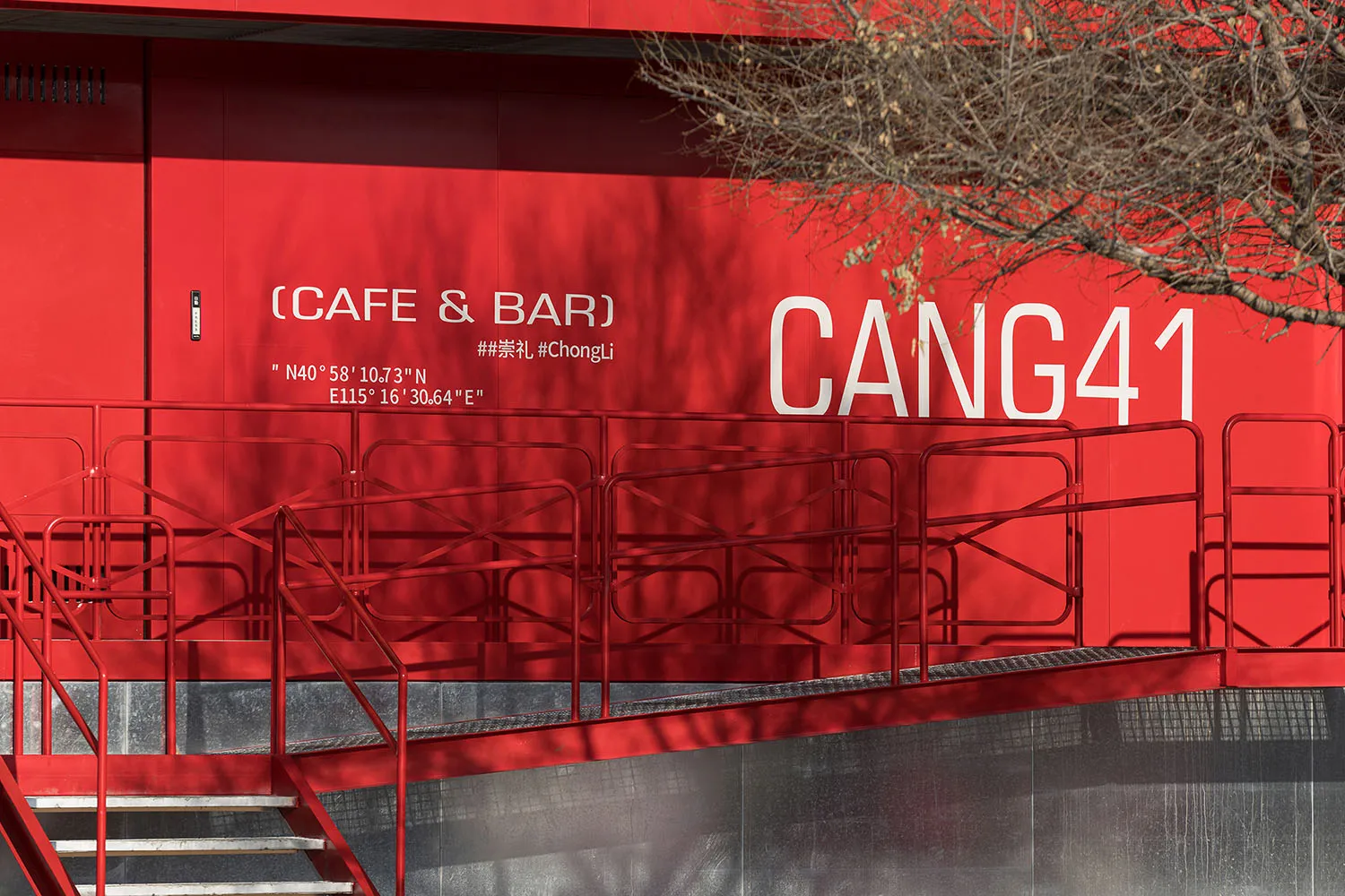 A red building with a staircase leading to a second floor, featuring railings and a possible restaurant or bar design