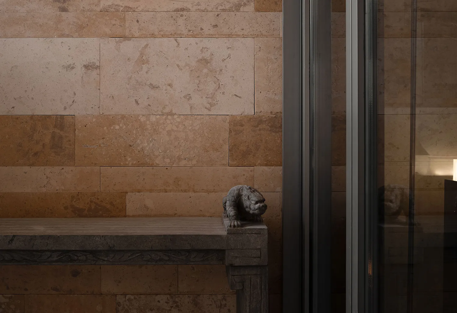 Dimly lit living room with a stone fireplace, brown tile surround, and a dog statue on the mantel