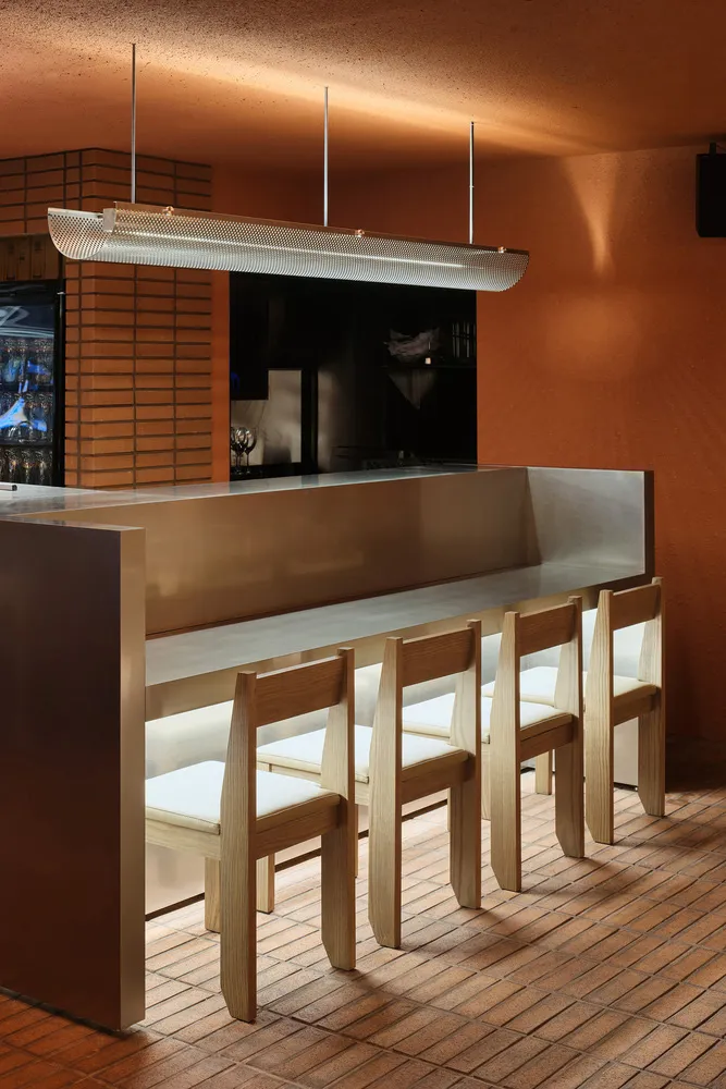 Modern bar with a metallic countertop, stools, and four chairs, creating a comfortable seating area for customers