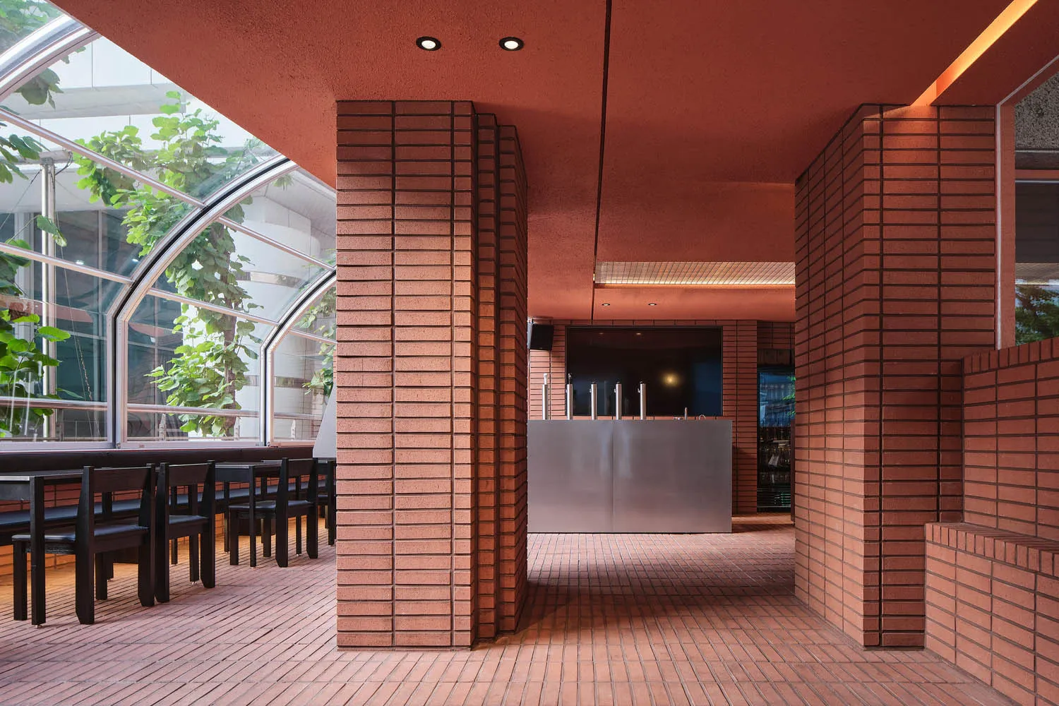紅磚牆溫馨餐廳內部，磁磚地板，餐桌周圍環繞座椅與酒瓶