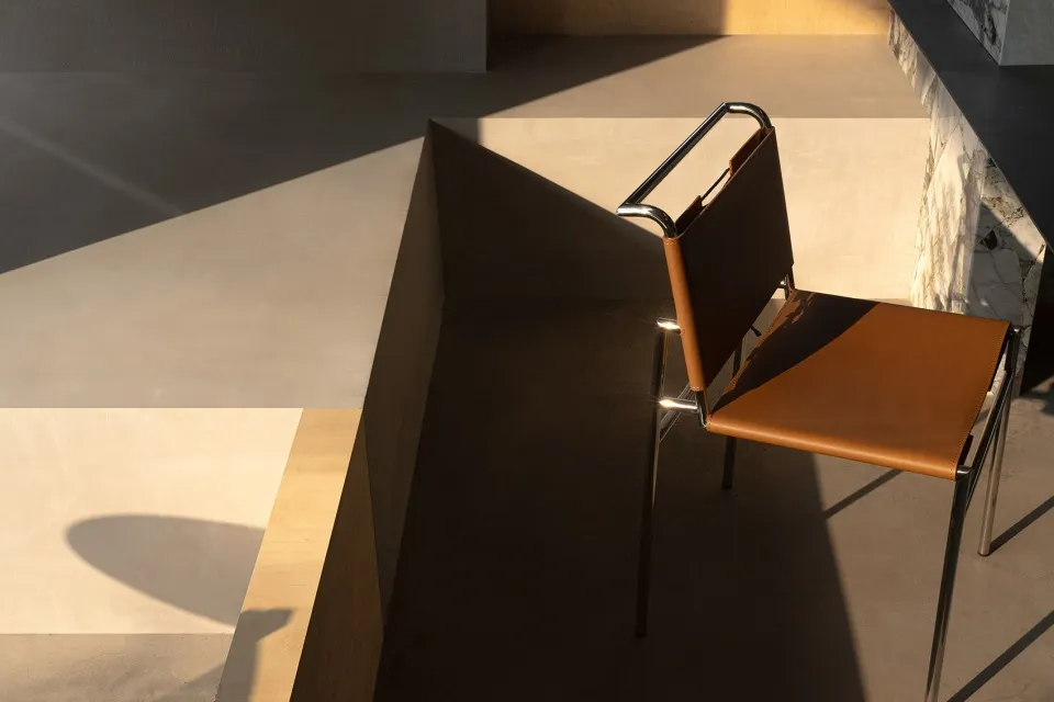 A leather chair sits on a hardwood floor in front of a wall, creating a comfortable and inviting atmosphere