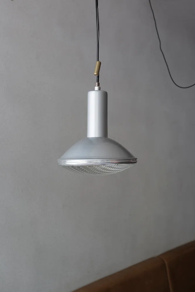 A modern room with a unique lamp hanging from the ceiling, surrounded by clean and minimalistic space with a focus on functionality