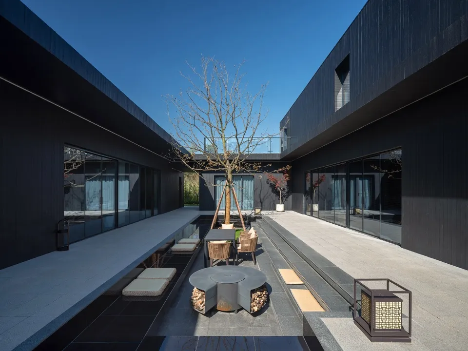 現代黑外牆住宅，擁有大片窗戶、椅子與餐桌，營造舒適溫馨氛圍