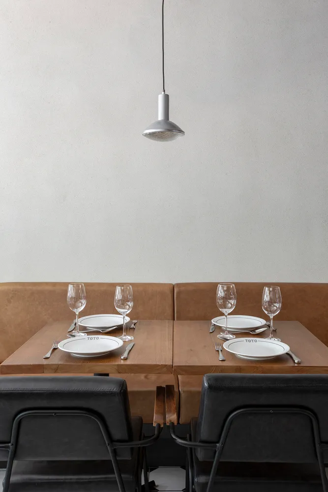 Elegant dining area with brown leather chairs, multiple tables set with wine glasses, plates, and cutlery, creating a sophisticated ambiance
