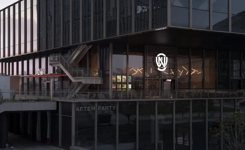 A modern building with a black facade and glass front, housing a water party venue with chairs and a staircase, creating a sophisticated and inviting atmosphere for socializing and entertainment