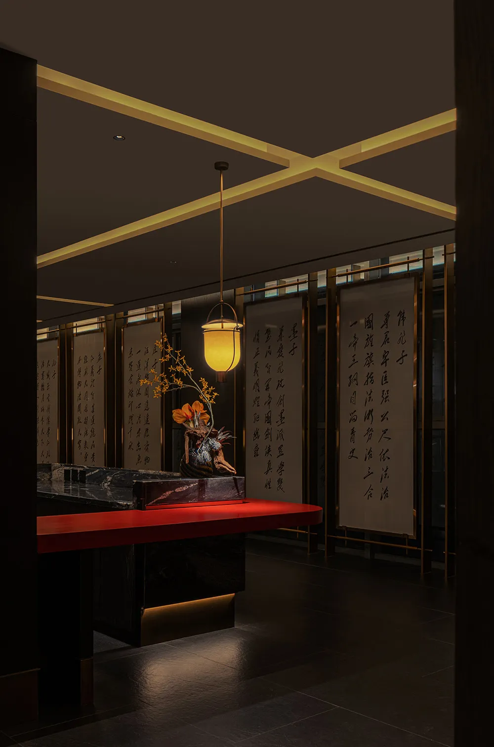 Dimly lit Asian restaurant interior with a red countertop, yellow lamp, and oriental writings on the walls