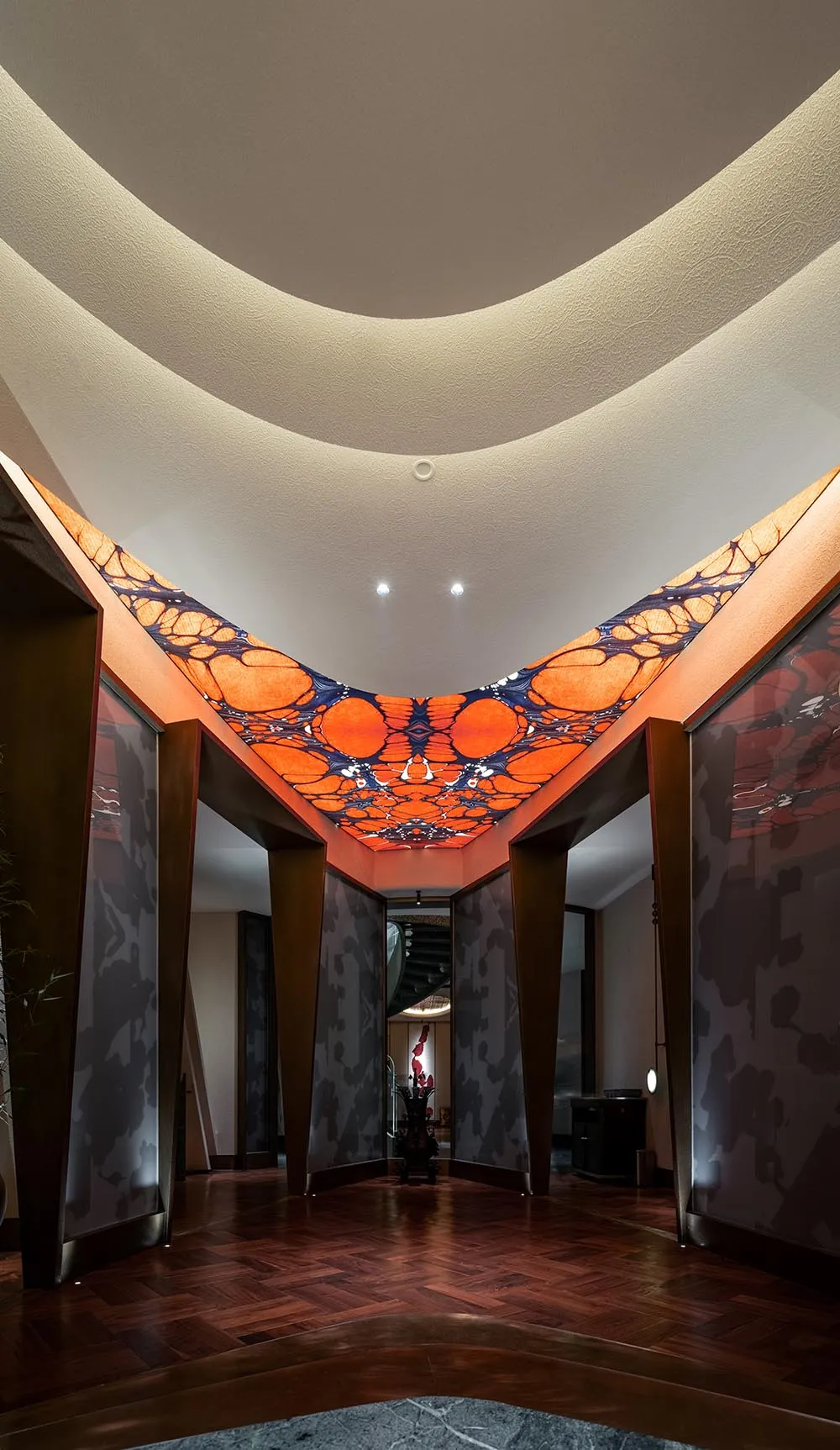 A modern interior space with a striking orange and red geometric design on the ceiling, creating a vibrant and energetic atmosphere
